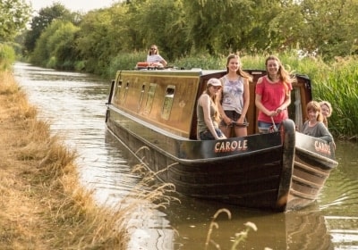 Family smiling on narrowboat, cruising on a canal